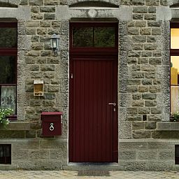 Charmantes Ferienhaus in Purnode, in den Ardennen, Belgien, mit rustikaler Steinfassade und einladender roter Tuer.