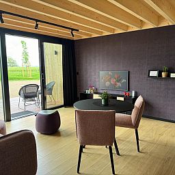 Gezellige woonkamer van Escapade Naturelle in de Ardennen, met uitzicht op terras en natuur.