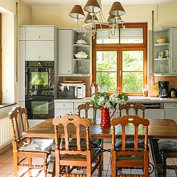 Gezellige keuken van Vakantiehuis La Rochette in Marche-en-Famenne, Ardennen, Belgie, met houten tafel en uitzicht op groene natuur.