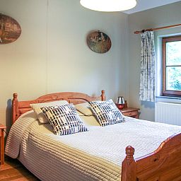 Sfeervolle slaapkamer in Vakantiehuis La Rochette, gelegen in Marche-en-Famenne, Ardennen, Belgie, met rustieke houten meubels.