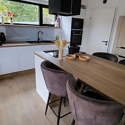 Modern kitchen of Cottage in Grandmenil, cottage in the Ardennes, Belgium, with wooden dining table and view of the green surroundings.