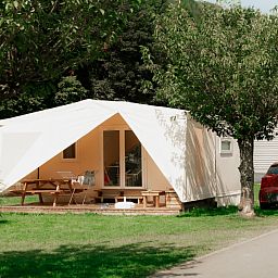 Coco Sweet met badkamer, een charmant tenthuis in La Roche-en-Ardenne, biedt een uitnodigend terras omgeven door groene natuur in de Ardennen.