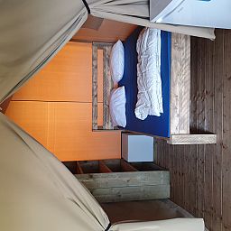 Gezellige slaapkamer in Safaritent, een glamping lodge in La Roche-en-Ardenne, Ardennen, Belgie met houten interieur en comfortabele bedden.