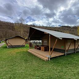 Safaritent in La Roche-en-Ardenne, Ardennen, Belgie, biedt een rustieke glamping ervaring met een uitnodigende veranda en omliggende natuur.