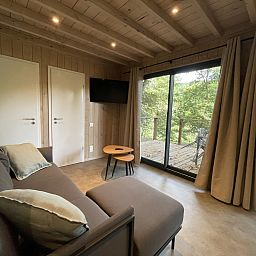 Gemuetliches Wohnzimmer der Ecolodge I 3 Bedrooms in Bouillon, Ardennen, mit Blick auf die gruene Natur von der bequemen Sitzecke aus.