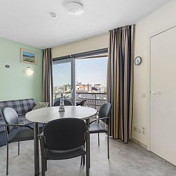 Gezellige woonkamer van Ocean Suites - 714 in Blankenberge, Belgische kust, met uitzicht op de stad vanaf het balkon.