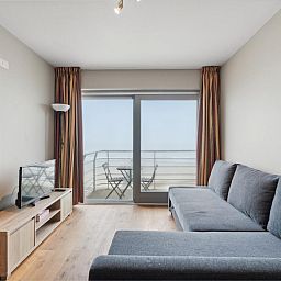 Gezellige woonkamer van Ocean Suites - 1004 in Blankenberge, Belgische kust, met uitzicht op zee vanaf het balkon van dit vakantieappartement.