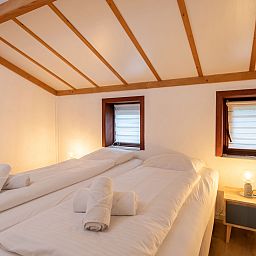 Gezellige slaapkamer in Vakantiehuis Strandhuis te Bredene, Belgische kust, met houten balkenplafond en knusse verlichting voor een ontspannen verblijf.