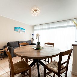 Cozy living room of Apartment Astrid 62/101 in Bredene, Belgian coast. Spacious indoor space with dining table and comfortable seating area.