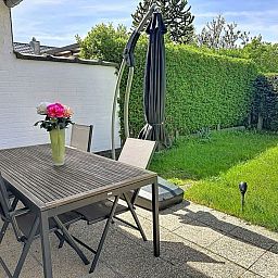 Gezellige eetkamer in Vakantiehuis Ruiterlaan, Bredene, Belgische kust, met houten meubels en uitzicht op de tuin.