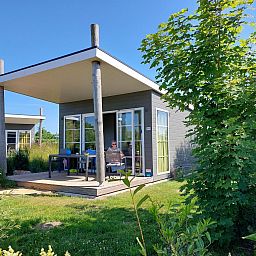 Comfort Lodge in Westende, Belgische kust, biedt een charmante vakantie-ervaring met een ruime veranda en groene omgeving.
