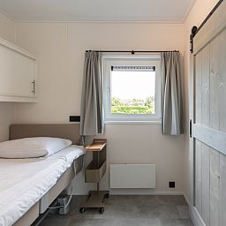 Knusse slaapkamer in Access Lodge, een vakantiehuis in Nieuwpoort aan de Belgische kust, met een comfortabel eenpersoonsbed en rustgevend uitzicht.