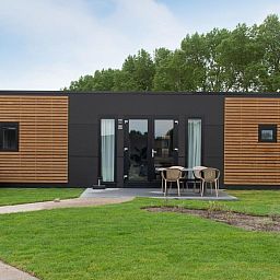 Wood Lodge in Nieuwpoort, Belgische kust, een moderne vakantieaccommodatie met veranda en groene omgeving, ideaal voor hondenliefhebbers.