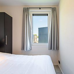 Slaapkamer in Wood Lodge, een vakantiehuis in Nieuwpoort aan de Belgische kust, met comfortabel bed en uitzicht op de omgeving.