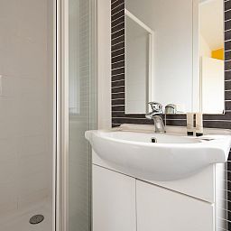 Moderne badkamer in Comfort Lodge, een vakantiehuis in Nieuwpoort aan de Belgische kust, met stijlvolle wastafel en douche.