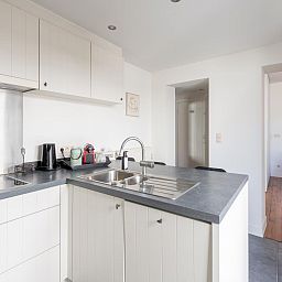 Moderne keuken in vakantiehuis Notre Dame, Nieuwpoort aan de Belgische kust, met elegante inrichting en toegang tot lichte woonkamer.