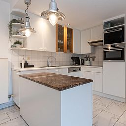 Moderne keuken in vakantiehuis Reigersnest in Nieuwpoort aan de Belgische kust, compleet met stijlvolle apparatuur en gezellige eetruimte.