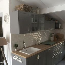 Moderne Kueche in "Het Toeval", einem Ferienhaus in Oostduinkerke an der belgischen Kueste, mit stilvollen grauen Schraenken und einer Arbeitsplatte aus Holz.