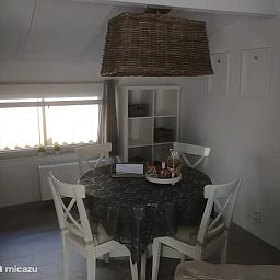 Gemuetliche Essecke in "Het Toeval", einem Ferienhaus in Oostduinkerke an der belgischen Kueste, mit einer rustikalen Haengelampe und einfallendem Tageslicht.