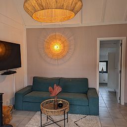 Gemuetliches Wohnzimmer im Ferienhaus Duinendaele II, De Panne, belgische Kueste mit bequemem Sofa und stimmungsvoller Beleuchtung.