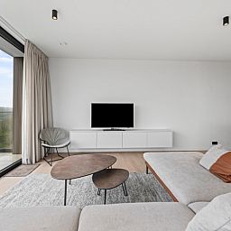 Modern living room of Penthouse 'Ter Elst' in De Panne, Belgian coast, with a view of nature from the terrace.