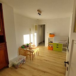Gemuetlicher Innenbereich des Ferienhauses "De Zji" in De Panne an der belgischen Kueste, mit Holzmoebeln und einer Spielecke fuer Kinder.