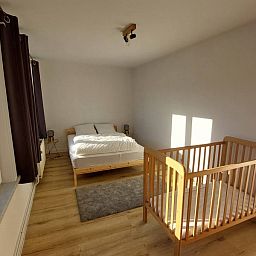 Gemuetliches Schlafzimmer im Ferienhaus "De Zji" in De Panne an der belgischen Kueste, mit einem bequemen Bett und einem Kinderbett fuer Familien.