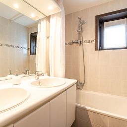 Moderne badkamer in Vakantiehuis Ingrid met dubbele wastafel, gelegen in De Haan aan de Belgische kust, perfect voor een ontspannen verblijf.