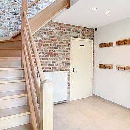 Gezellige entree met houten trap in Hoeve Langhof vakantiehuis, De Haan aan de Belgische kust.