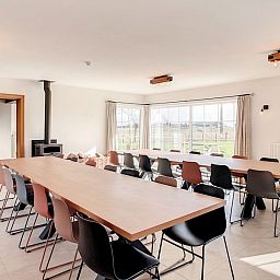 Eetkamer met lange tafels in Hoeve Langhof vakantiehuis, De Haan, ideaal voor groepsdiners.