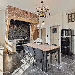 Gezellige keuken in Huis Potaerde, een vakantiehuis in Brussel, met een rustieke eettafel en authentieke details voor een warme sfeer.