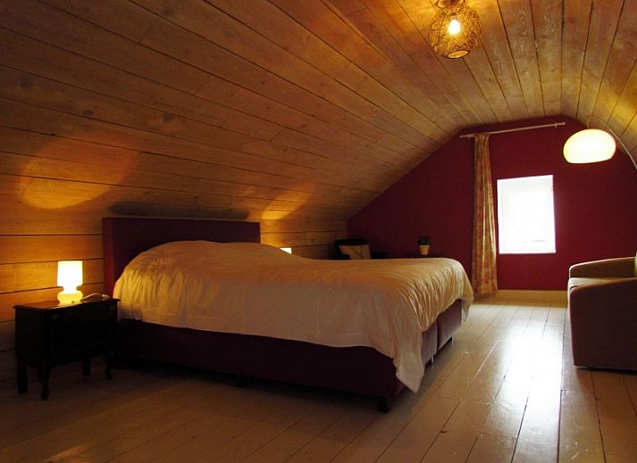 Gemuetliches Schlafzimmer im Ferienhaus Hof ter Harte, Ypern, Westflandern, mit Holzdecke und sanfter Beleuchtung.