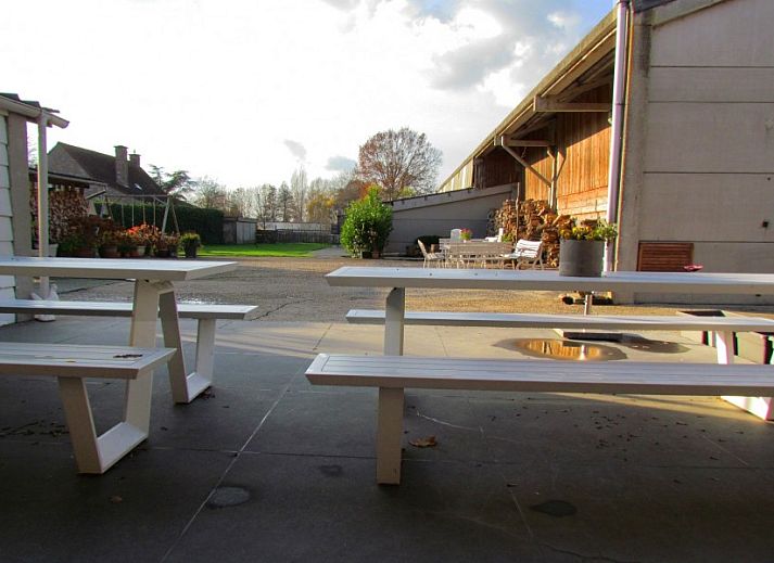 Aussenansicht des Ferienhauses Hof ter Harte, Ypern, Westflandern, mit roten Akzenten und bluehenden Hortensien.