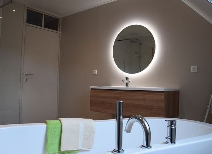 Veranda bij Reutelhoeve vakantiehuis in Zonnebeke, West-Vlaanderen met bloemen en terrasmeubilair.