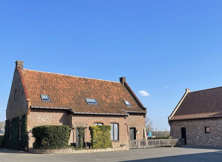 Gezellige woonkamer in Reutelhoeve vakantiehuis in Zonnebeke, West-Vlaanderen met open haard en comfortabele stoelen.