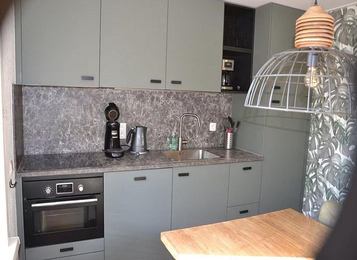 Geraeumige Terrasse der Villa Belle Haan in De Haan, Belgien, mit bequemen Sitzgelegenheiten und Sonnenschirmen fuer ein entspannendes Ferienerlebnis.