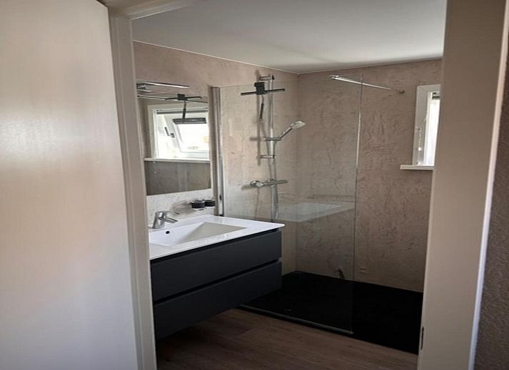 Geraeumige Terrasse der Villa Belle Haan in De Haan, Belgien, mit bequemen Sitzgelegenheiten und Sonnenschirmen fuer ein entspannendes Ferienerlebnis.