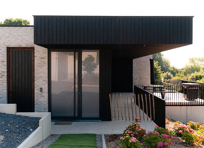 Geraeumige Terrasse des Ferienhauses in Westouter, Westflandern, mit Blick auf die gruene Umgebung und moderne Architektur.