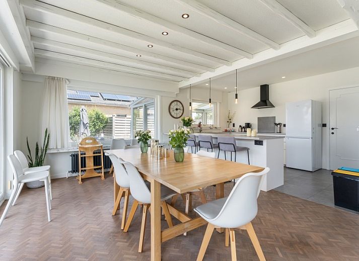 Lichte eetruimte in Villa Renee, De Haan, Belgische kust, met uitzicht op terras en tuin.