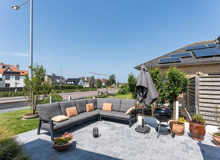 Stijlvolle woonkamer in Villa Renee, De Haan, Belgische kust, met leren banken en grote ramen.