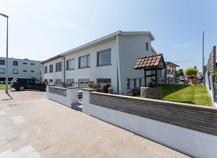 Stijlvolle woonkamer in Villa Renee, De Haan, Belgische kust, met leren banken en grote ramen.