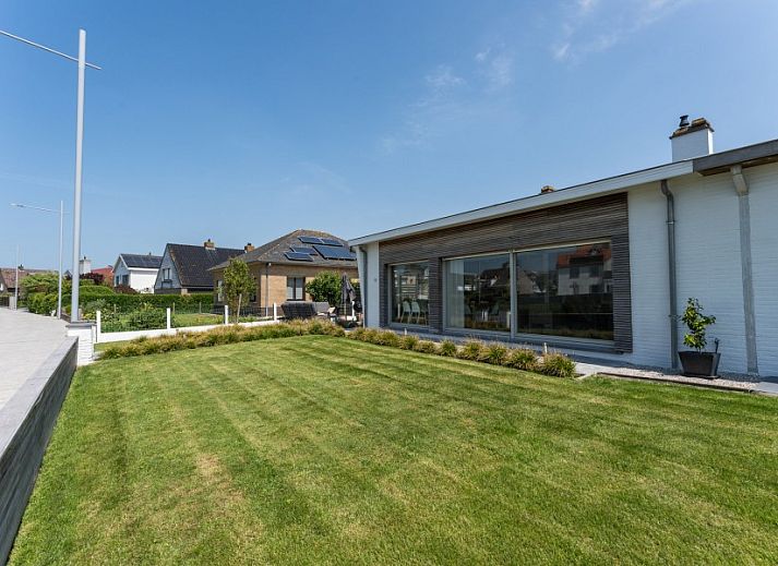 Stijlvolle woonkamer in Villa Renee, De Haan, Belgische kust, met leren banken en grote ramen.