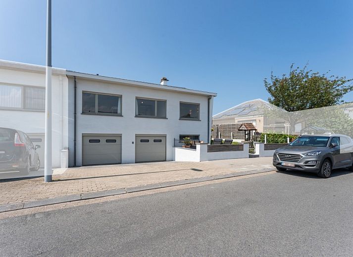 Stijlvolle woonkamer in Villa Renee, De Haan, Belgische kust, met leren banken en grote ramen.
