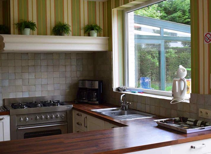 Front view of vacation home BK038 in Koksijde, West Flanders, with charming facade and green surroundings.