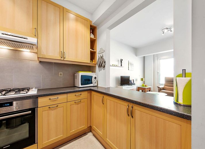 Moderne keuken in vakantiehuis Azcona Twee, Koksijde, West-Vlaanderen, Belgie met houten kasten en moderne apparatuur.