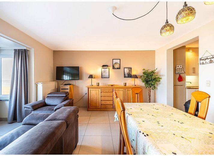 Gezellige woonkamer van vakantiehuis Cortina tweede in Koksijde, West-Vlaanderen met comfortabele zithoek en eethoek voor een ontspannen verblijf.