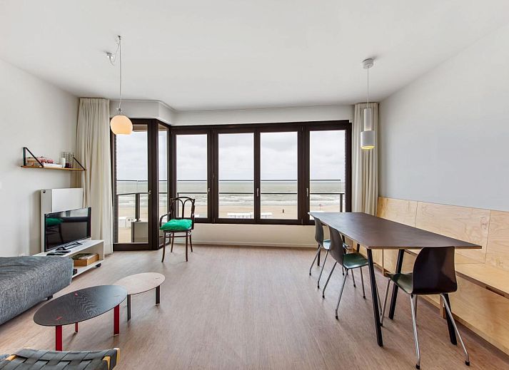 Ruime woonkamer van vakantiehuis De Meeuwen derde in Koksijde, Belgie, met panoramisch uitzicht op de kustlijn van West-Vlaanderen.