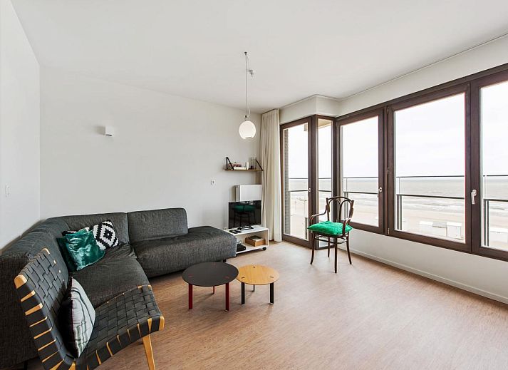 Ruime woonkamer van vakantiehuis De Meeuwen derde in Koksijde, Belgie, met panoramisch uitzicht op de kustlijn van West-Vlaanderen.