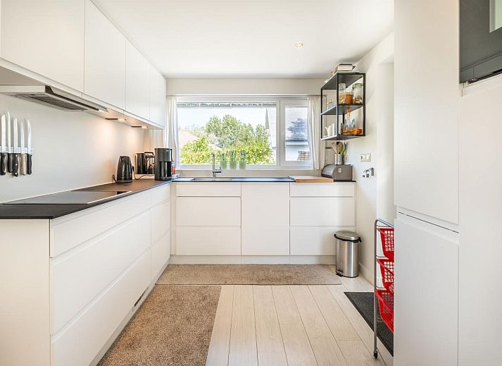 Ruim terras bij vakantiehuis Guillaume in Koksijde, West-Vlaanderen, Belgie, omgeven door groen en voorzien van comfortabele zitgelegenheden.