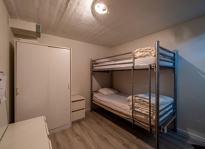 Gezellige eetruimte in vakantiehuis Guillaume in Koksijde, West-Vlaanderen, met kleurrijke stoelen en uitzicht op de lichte woonkamer.